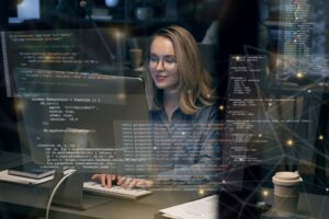 Mulher programando em um computador. Códigos na tela.